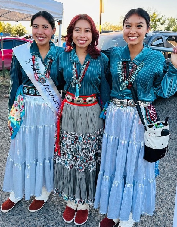Three young Diné women in traditional dress.